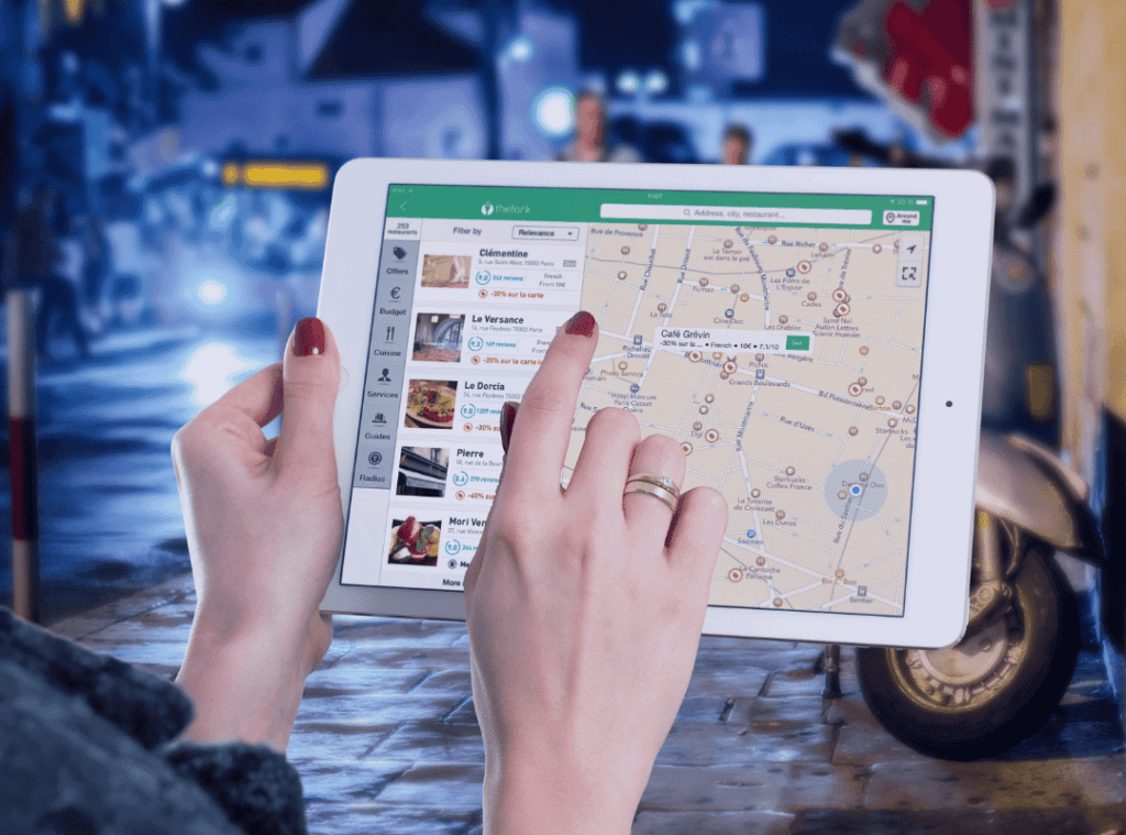 mulher segurando tablet com rotas de restaurantes